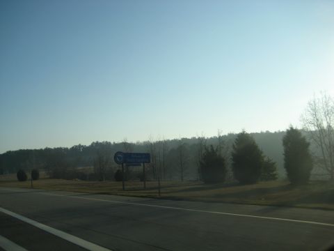 2001 Ford Crown Victoria - A roadside scene with trees and a sign under a clear blue sky.