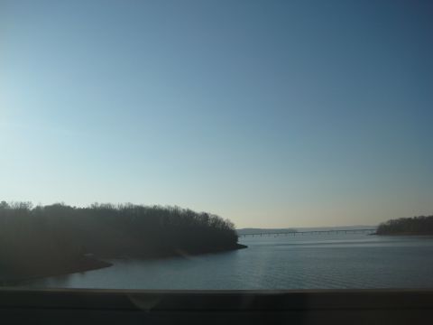 2001 Ford Crown Victoria - A wide shot of a calm lake with a long bridge spanning across it under a clear blue sky.