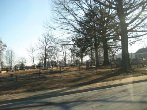 2001 Ford Crown Victoria - A view of a cemetery with gravestones and bare trees, seen on a sunny day.