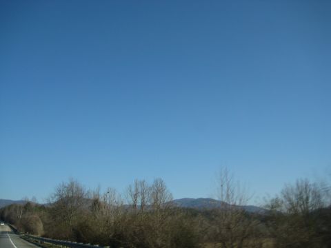 2001 Ford Crown Victoria - View from a vehicle traveling on a highway, showing trees, mountains, and a clear blue sky.
