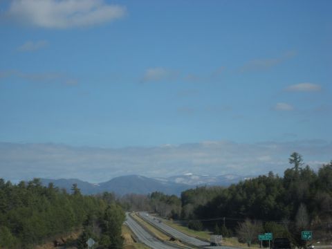 2001 Ford Crown Victoria - A highway winds through a forest with distant mountains under a blue sky.
