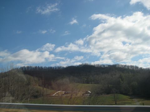 2001 Ford Crown Victoria - A scenic view of a rural landscape with rolling hills and scattered buildings under a bright, cloudy sky.