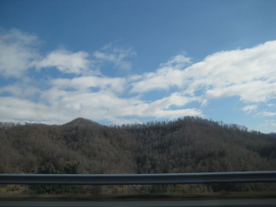 View of mountains and sky from a car window. Supermotors.net logo visible