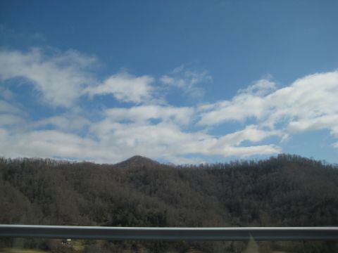 2001 Ford Crown Victoria - A scenic view of mountains under a cloudy blue sky, captured from a vehicle.
