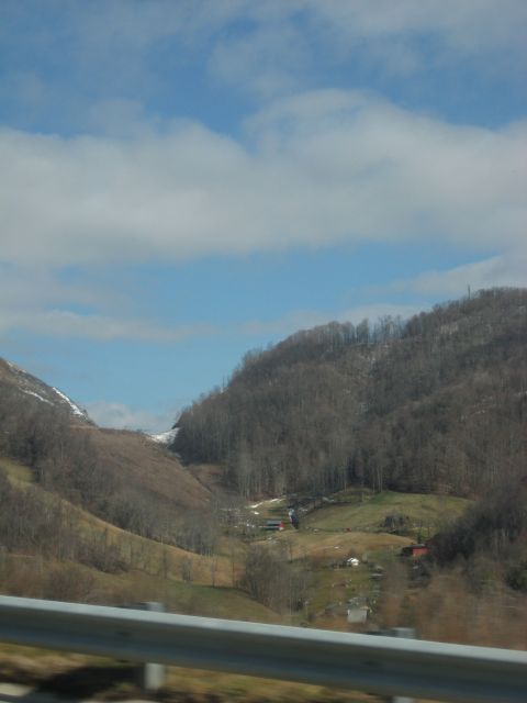 2001 Ford Crown Victoria - A scenic view of a mountain valley dotted with houses and bare trees, under a partly cloudy sky.