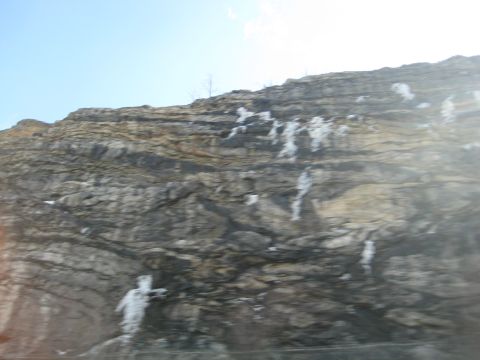 2001 Ford Crown Victoria - A rocky cliff face with patches of snow is visible against a clear blue sky.