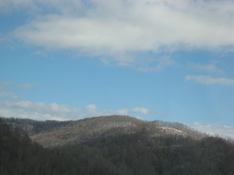 2001 Ford Crown Victoria - A scenic view of tree-covered mountains under a partly cloudy sky, with a Supermotors logo visible in the lower right corner.