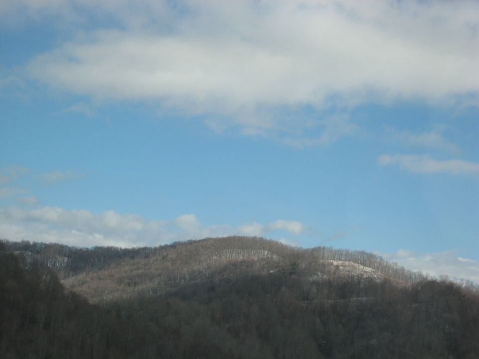 Mountains under a blue sky with clouds, Supermotors logo in corner