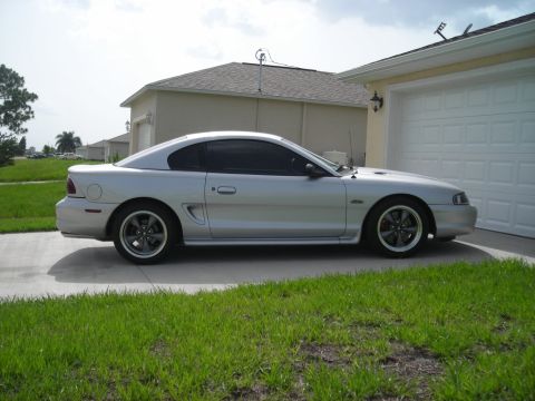 1998 Ford Mustang - Side view of a silver 1998 Ford Mustang coupe parked on a driveway.