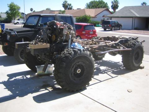 1994 Ford Bronco - A custom off-road vehicle chassis is undergoing work, with other vehicles parked nearby.
