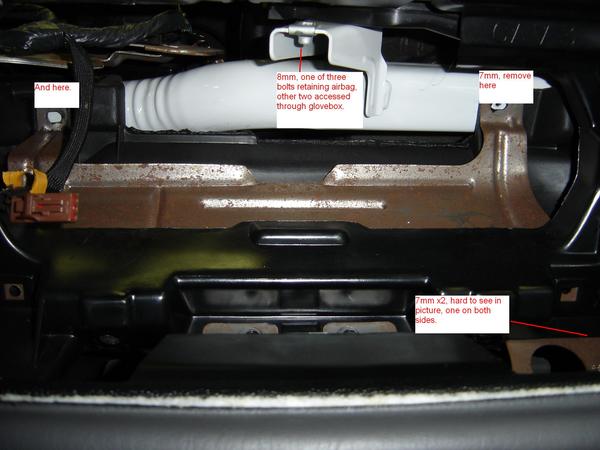 Car interior showing metal brackets, white plastic tubing, and wiring. Text annotations indicate bolt sizes and locations