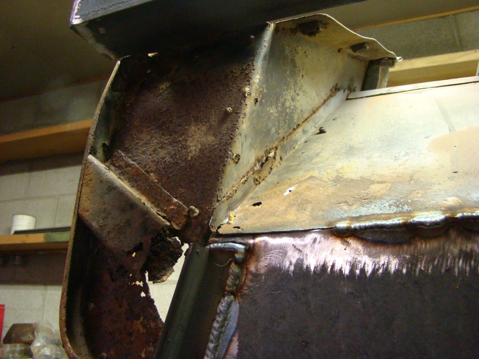 Heavily rusted metal frame section with visible welds and some new metal patches