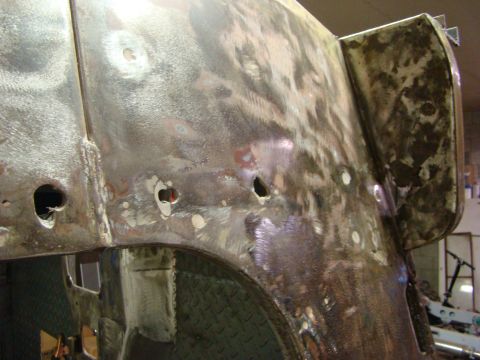 1948 Jeep Wrangler - Close-up of a heavily repaired and unpainted vehicle body panel, indicating extensive bodywork.