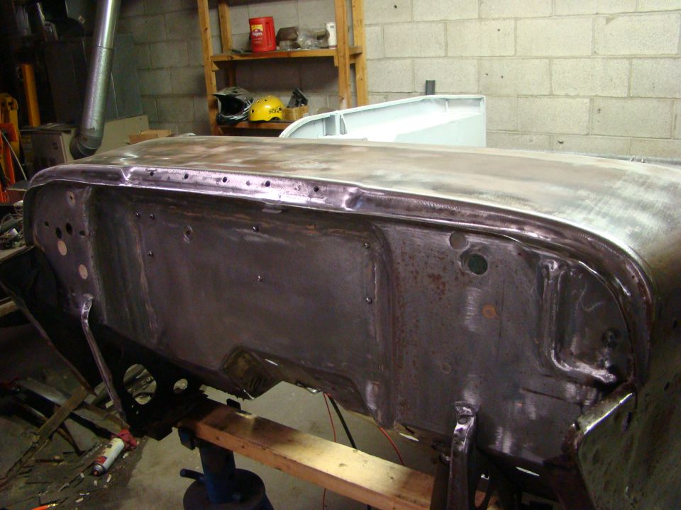Car body panel in workshop, showing metalwork and holes