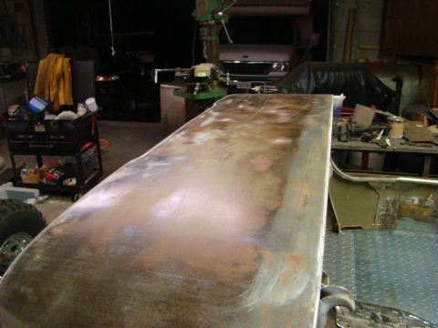 1948 Jeep Wrangler - A close-up of a heavily rusted metal panel, likely a car part, in a workshop setting.