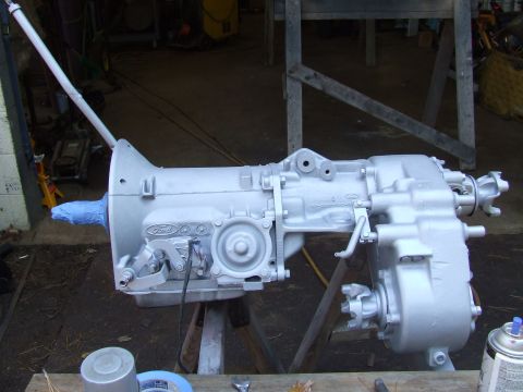 1967 Ford Bronco - Silver-painted Ford transmission and transfer case assembly on sawhorses, ready for installation.