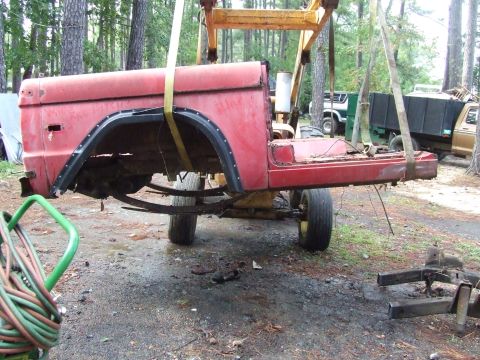 1967 Ford Bronco - The body of a 1967 Ford Bronco is suspended by a crane, revealing its side profile and undergoing what appears to be a restoration or disma…