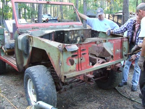 1967 Ford Bronco - A group of men are gathered around a disassembled vehicle, appearing to be in the process of restoration or repair.