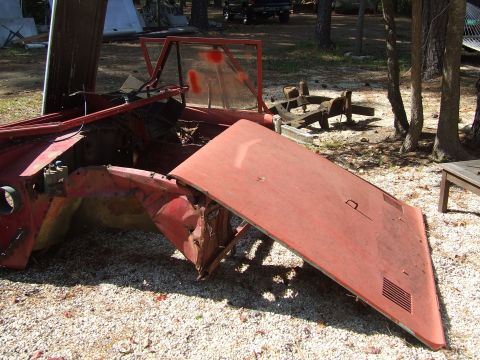 1967 Ford Bronco - Disassembled red vehicle parts lie on gravel, with a watermark at the bottom right.