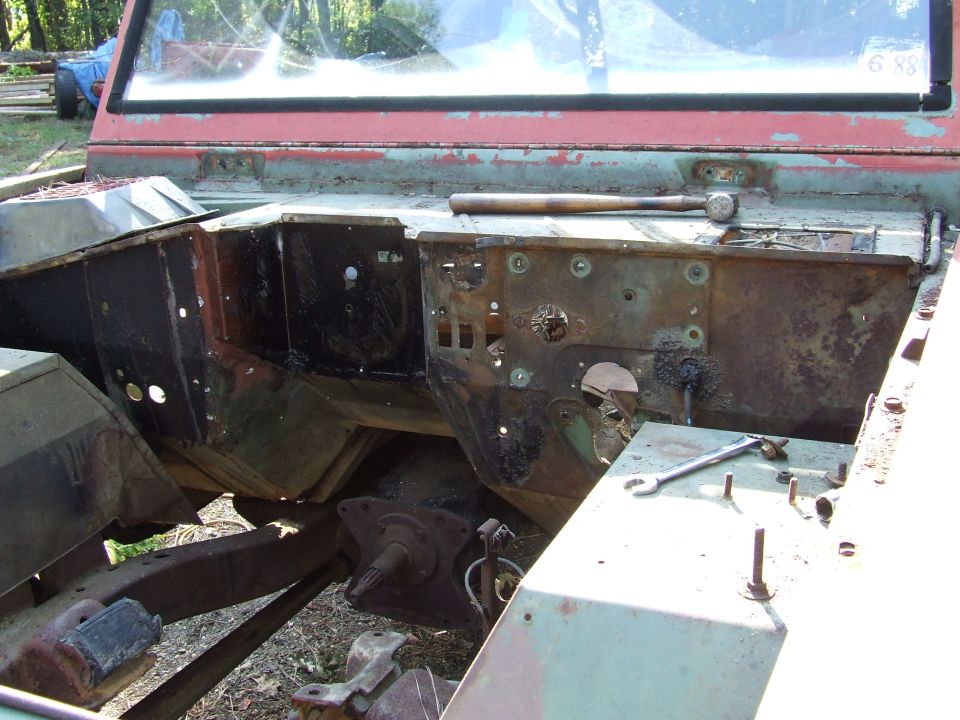 rusted firewall and inner fender wells of a vehicle undergoing restoration, with tools visible on top