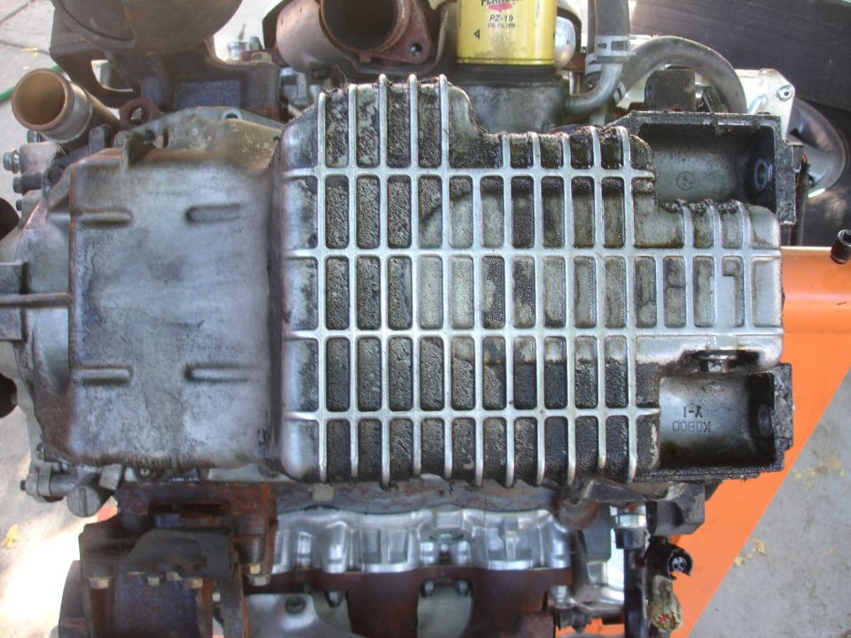 Engine oil pan with a ribbed heat sink and visible oil residue. Part number K0800 is stamped on the side