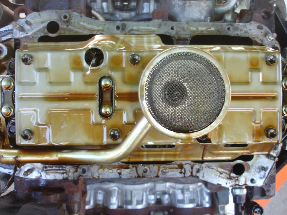 engine oil pan with pickup tube and screen, covered in oil