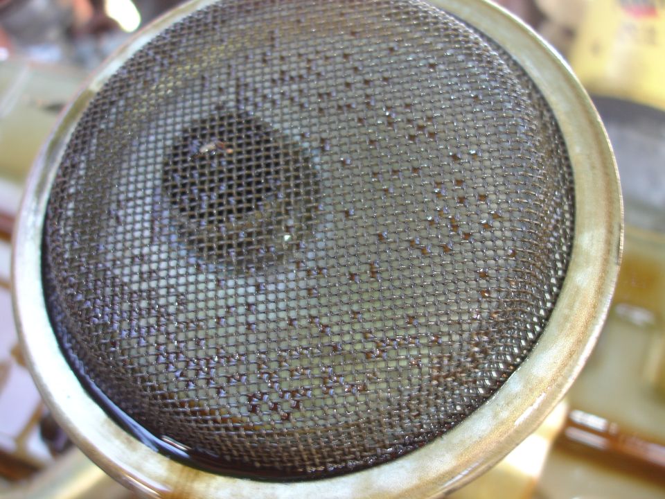 Oil strainer with debris caught in mesh