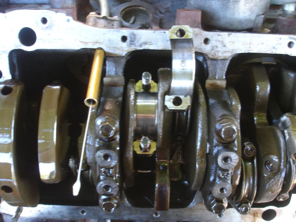 Engine crankshaft with connecting rods and bearing caps visible. A yellow dipstick tube is also present