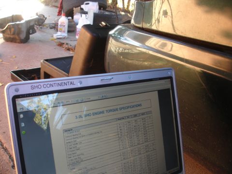 1993 Ford Taurus - A laptop displays engine torque specifications for a 3.0L SHO engine, positioned near a vehicle.