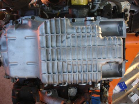 1993 Ford Taurus - A close-up view of an engine's oil pan, showing its ribbed construction and some stamped markings.