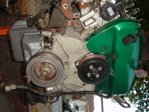 1993 Ford Taurus - Close-up view of an engine component, a green cover and various pulleys.