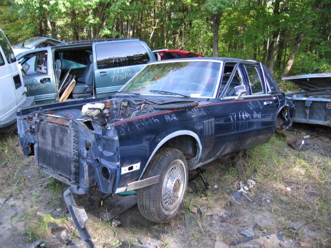 2001 Ford Crown Victoria - Photograph of a wrecked sedan with parts markings in a junkyard, not a technical document.