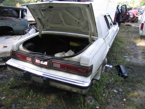 2001 Ford Crown Victoria - Photograph of a white Chrysler sedan in a junkyard, not a technical document.