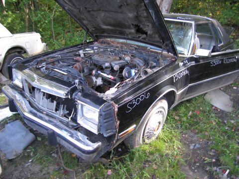 2001 Ford Crown Victoria - Photograph of a black Chrysler coupe in a junkyard, not a technical document.