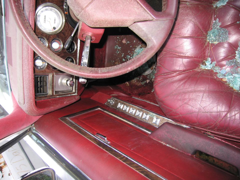 Red leather sedan interior with broken glass on seats and disassembled dash