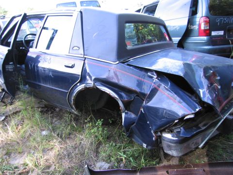 2001 Ford Crown Victoria - Photograph of a wrecked dark blue sedan in a junkyard, not a technical document.