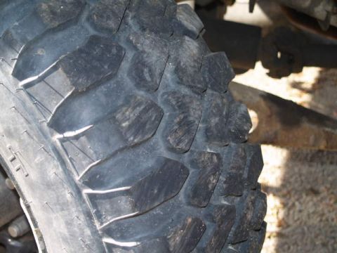 1996 Ford Bronco - A close-up, angled view of a knobby off-road tire tread on a vehicle. The tire shows significant wear and is mounted on a wheel partially v…