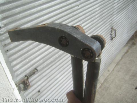 1987 Suzuki Samurai - Photograph of a fabricated curved steel lever/linkage part, not a technical document.