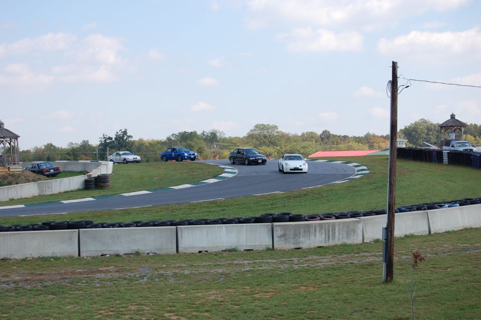 White sports car on a race track with other cars visible.