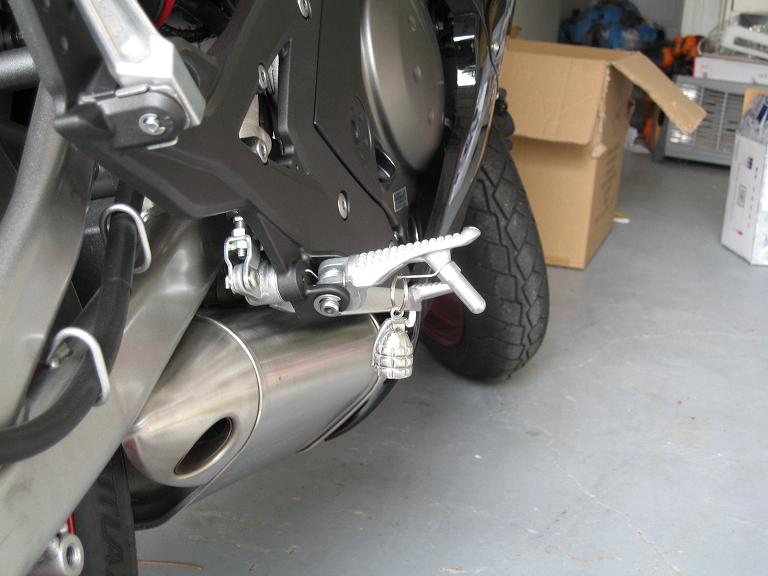 Motorcycle rear footpeg and exhaust with grenade keychain.