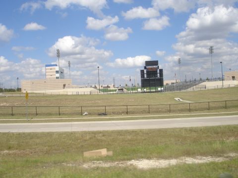 1989 Ford Bronco - A wide shot of a football stadium with a scoreboard and bleachers under a cloudy blue sky.