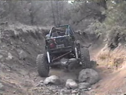 Off-road vehicle climbing a rocky, narrow trail.