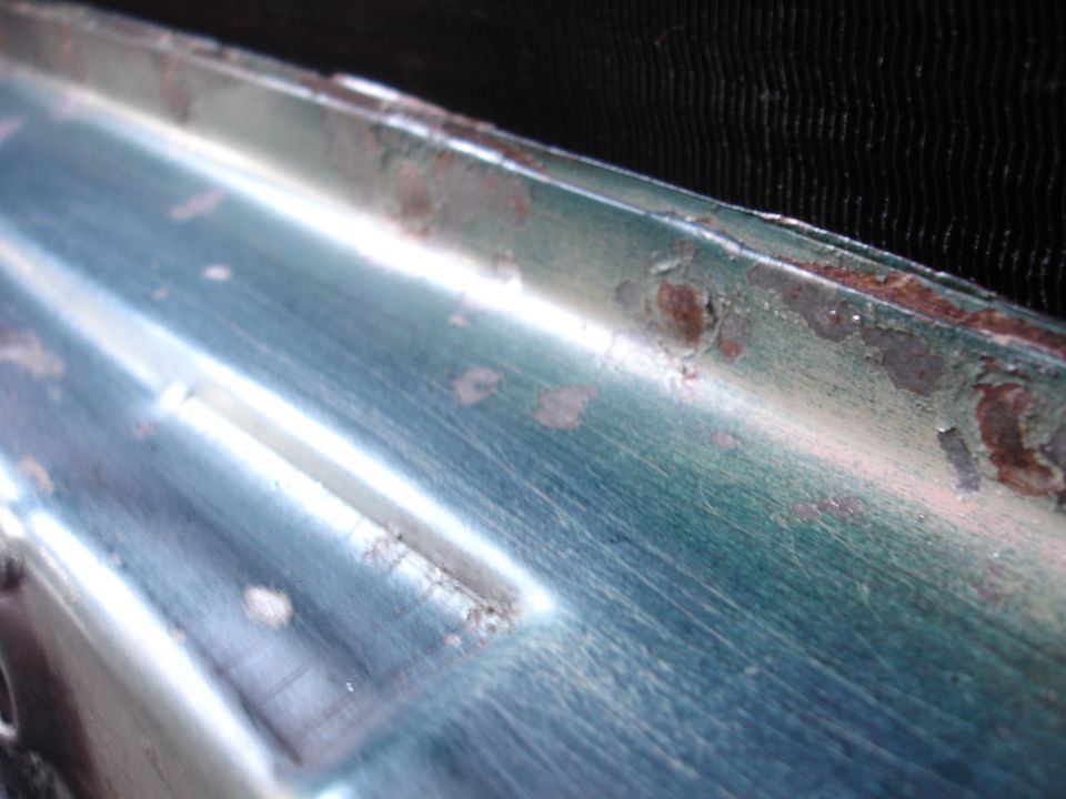 Close-up of a teal vehicle fender with rust and peeling paint.
