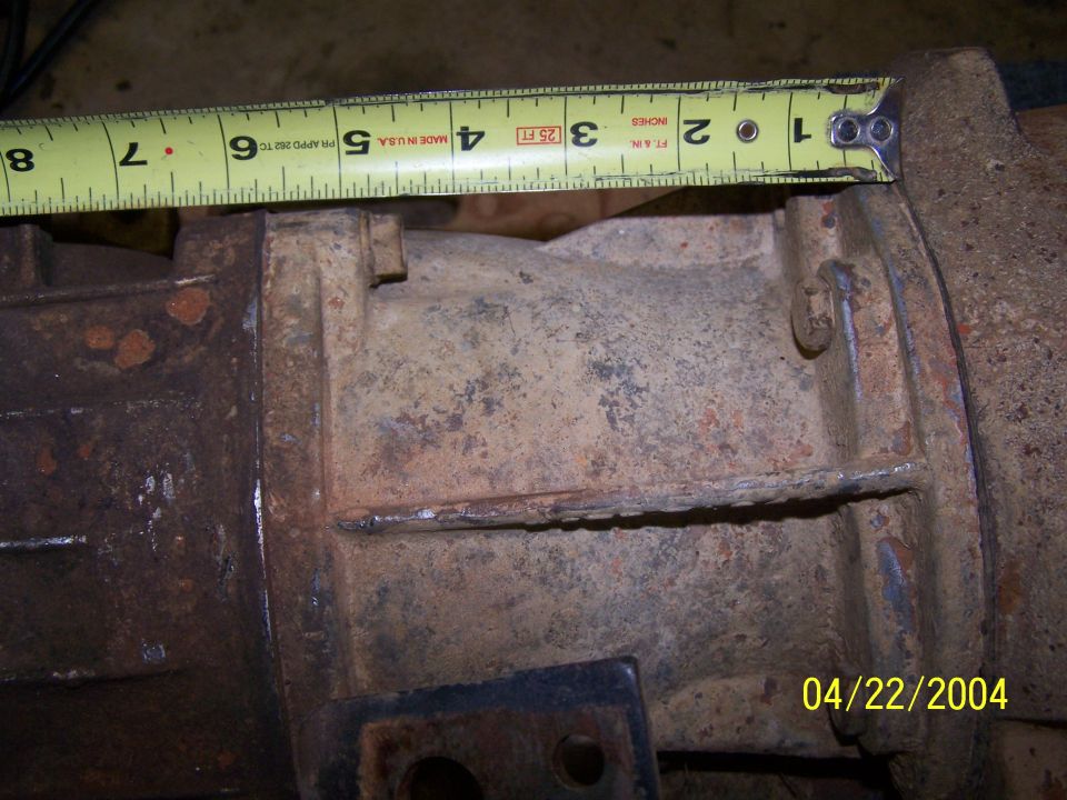 rusted metal component with tape measure showing 4 inches