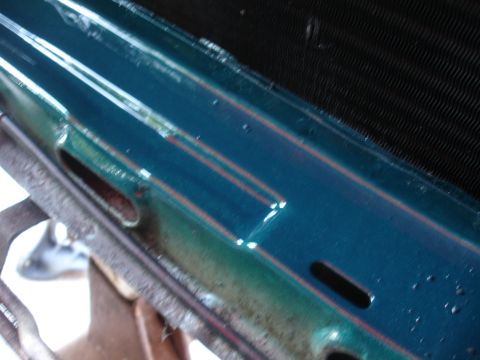 1993 Ford Taurus - Close-up view of a teal painted metal component red pinstripes and a black grille, likely a part of a vehicle's exterior.