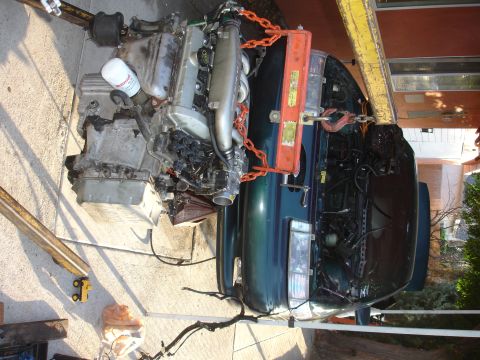 1993 Ford Taurus - Engine hoist lifting the engine out of a green 1993 Ford Taurus.