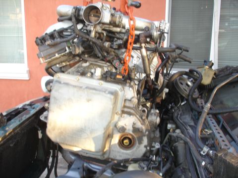 1993 Ford Taurus - Engine removal in progress, showing complex wiring and plumbing attached to the engine block.