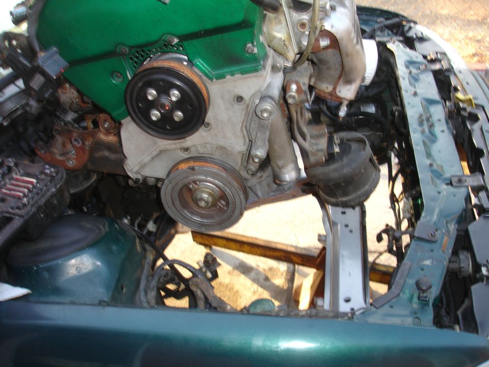 engine being worked on inside a car's engine bay, green engine cover visible