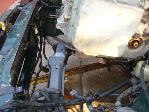 1993 Ford Taurus - The engine bay of a 1993 Ford Taurus shows green body panels and a silver oil pan, indicating ongoing repairs.