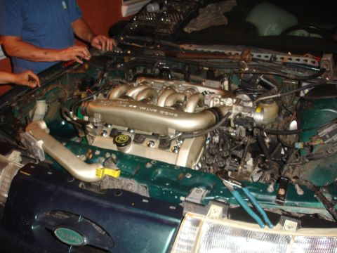 1993 Ford Taurus - Mechanics work on the engine of a 1993 Ford Taurus, with tools visible in the engine bay.